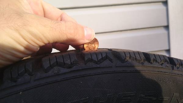 checking tread depth on used tire with penny